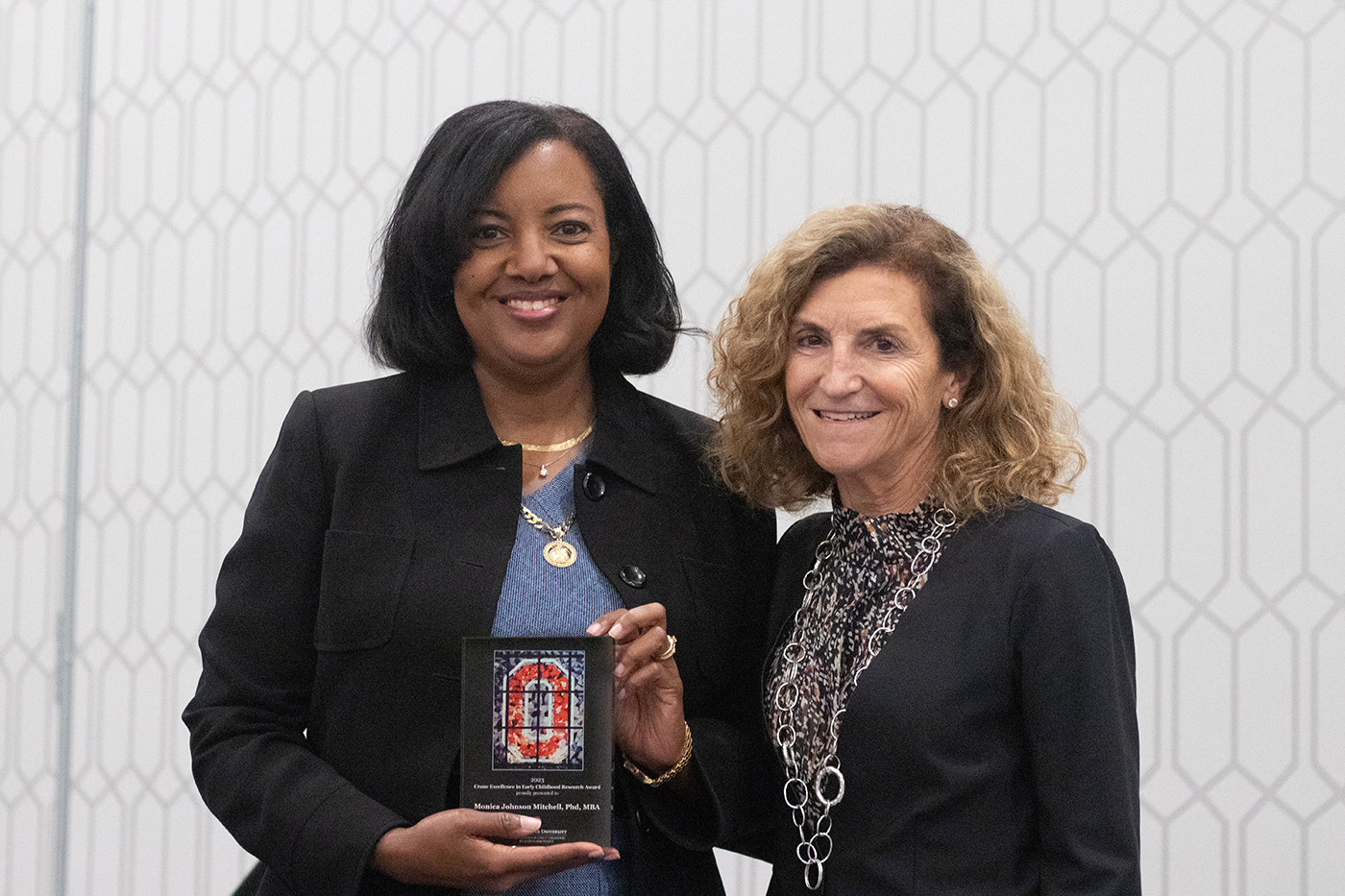 Dr. Monica Johnson Mitchell of Cincinnati Children’s Hospital, left, holds a plaque as a recipient of a Crane Excellence in Early Childhood Award as she stands next to Tanny Crane, president and CEO of Crane Group.