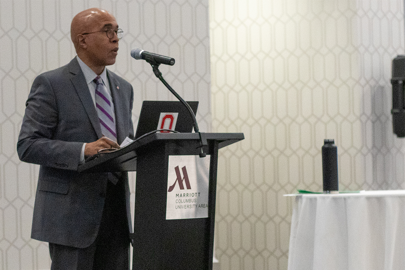 Donald Pope-Davis, Dean of the College of Education and Human Ecology at The Ohio State University, addresses those attending the 2023 Crane Symposium on Children. Pope-Davis, wearing a suit and tie, stands behind a podium and speaks into a microphone attached to the podium.