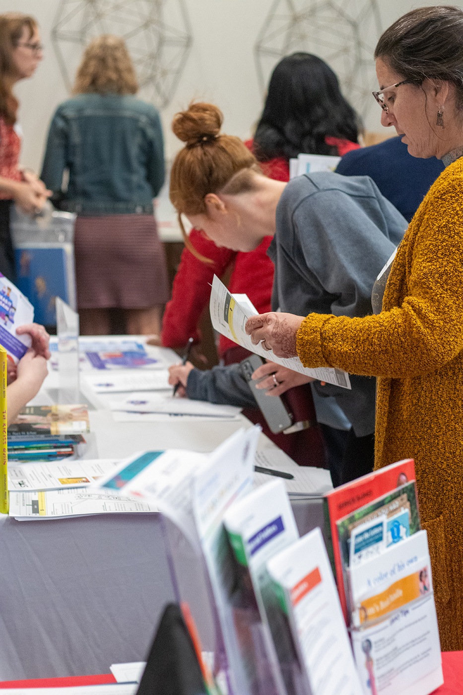 Attendees examine handouts at tables in an exhibition hall during the 2023 Crane Symposium on Children.