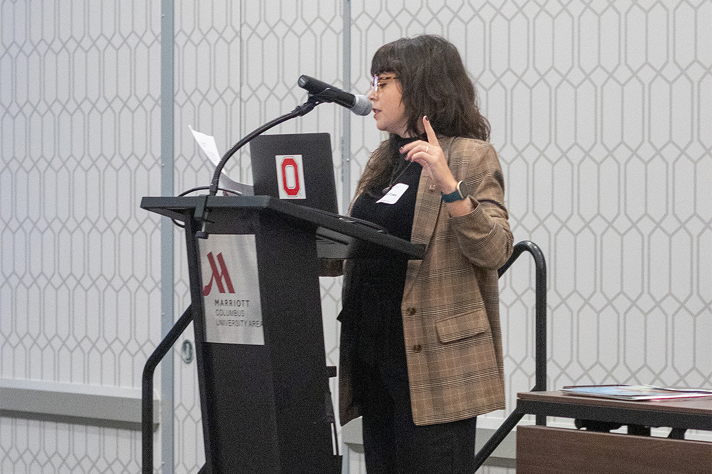 Jamie O'Leary, the Crane Center's associate director of policy and external affairs, stands behind a podium and speaks into a microphone attached to the podium during the 2023 Symposium on Children.