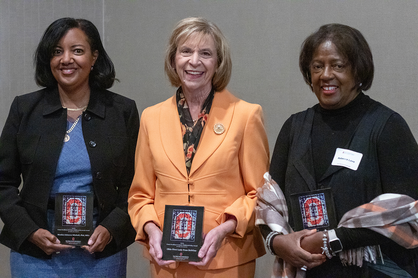 The recipients of the 2023 Crane Excellence in Early Childhood Awards: From left, Dr. Monica Johnson Mitchell, professor of pediatrics at Cincinnati Children’s Hospital; Fran DeWine, First Lady of Ohio; and Rebecca Love, director of Early Childhood Education for the Franklin County Board of Developmental Disabilities. The three women are standing facing the camera. Each is holding the award plaque, which shows an image of a "Block O," the logo for The Ohio State University.