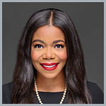 Headshot of Erica Crawley, wearing a black dress, pearl necklace, and smiling at the camera against a dark background.