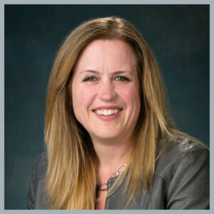 Laura Justice smiles at the camera in a gray jacket.